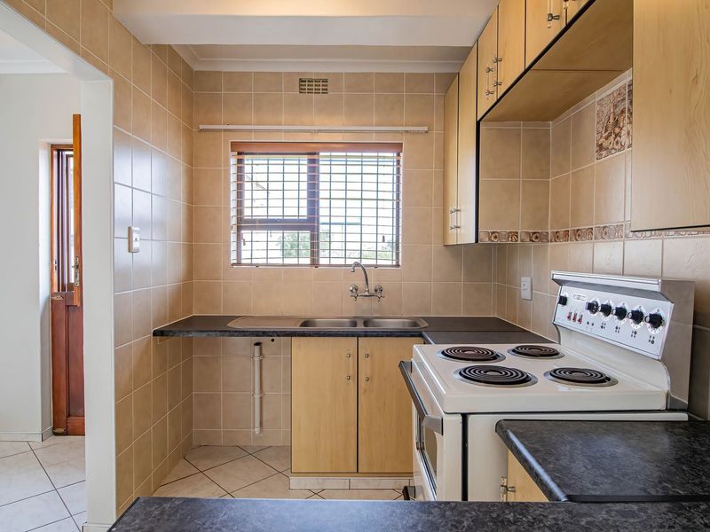 A functional kitchen featuring built-in cabinetry, laminate countertops, a double basin sink, and a freestanding electric stove with tiled splashbacks.