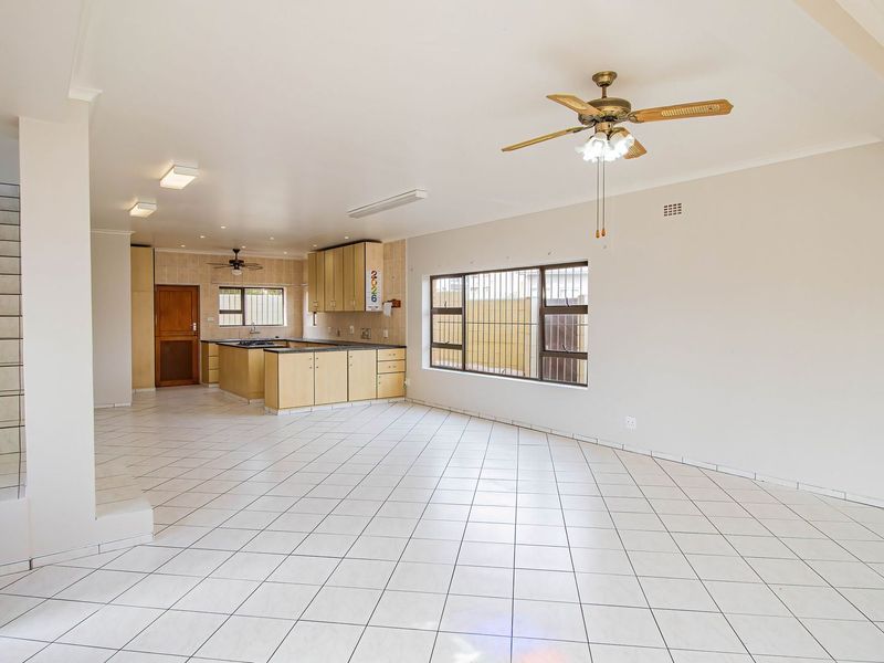 Spacious open-plan living and kitchen area featuring tiled flooring, built-in cabinetry, and a staircase, offering a bright and versatile layout.