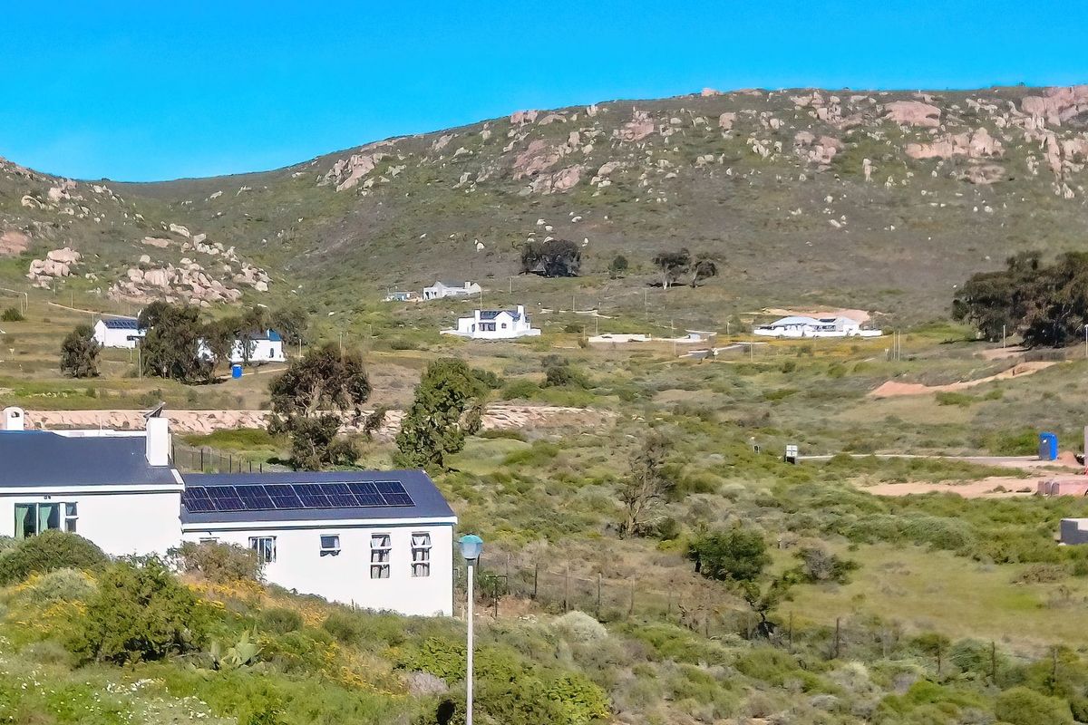 A scenic elevated view of the residential estate landscape featuring natural terrain, scattered homes, and solar panel installations.