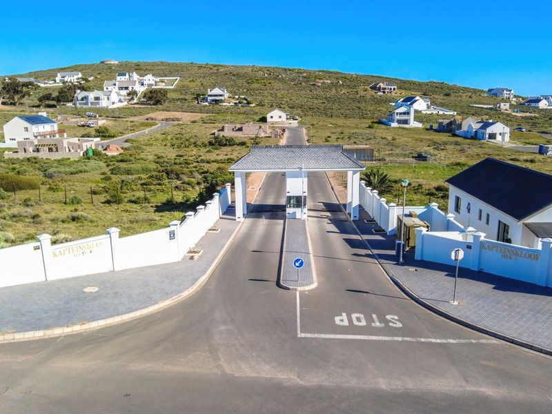 Aerial view of the secure gated entrance to the residential estate, featuring a paved driveway, security gatehouse, and surrounding perimeter walls.