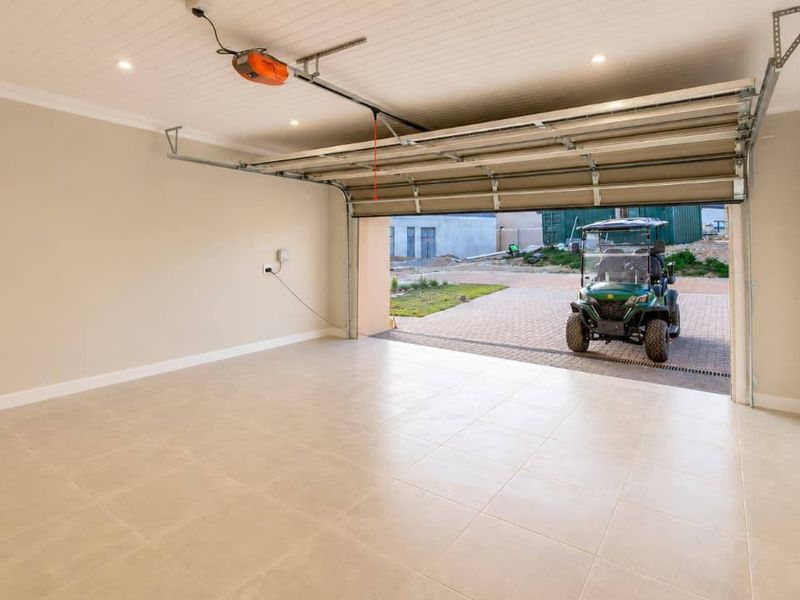 Spacious, well-maintained double garage featuring tiled flooring, recessed lighting, and a modern sectional door with an automated motor.