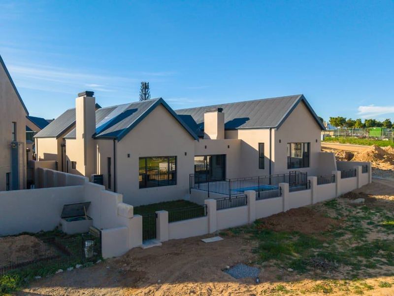 Aerial view of the rear elevation featuring a swimming pool, patio area, and perimeter walling with a modern metal roof design.