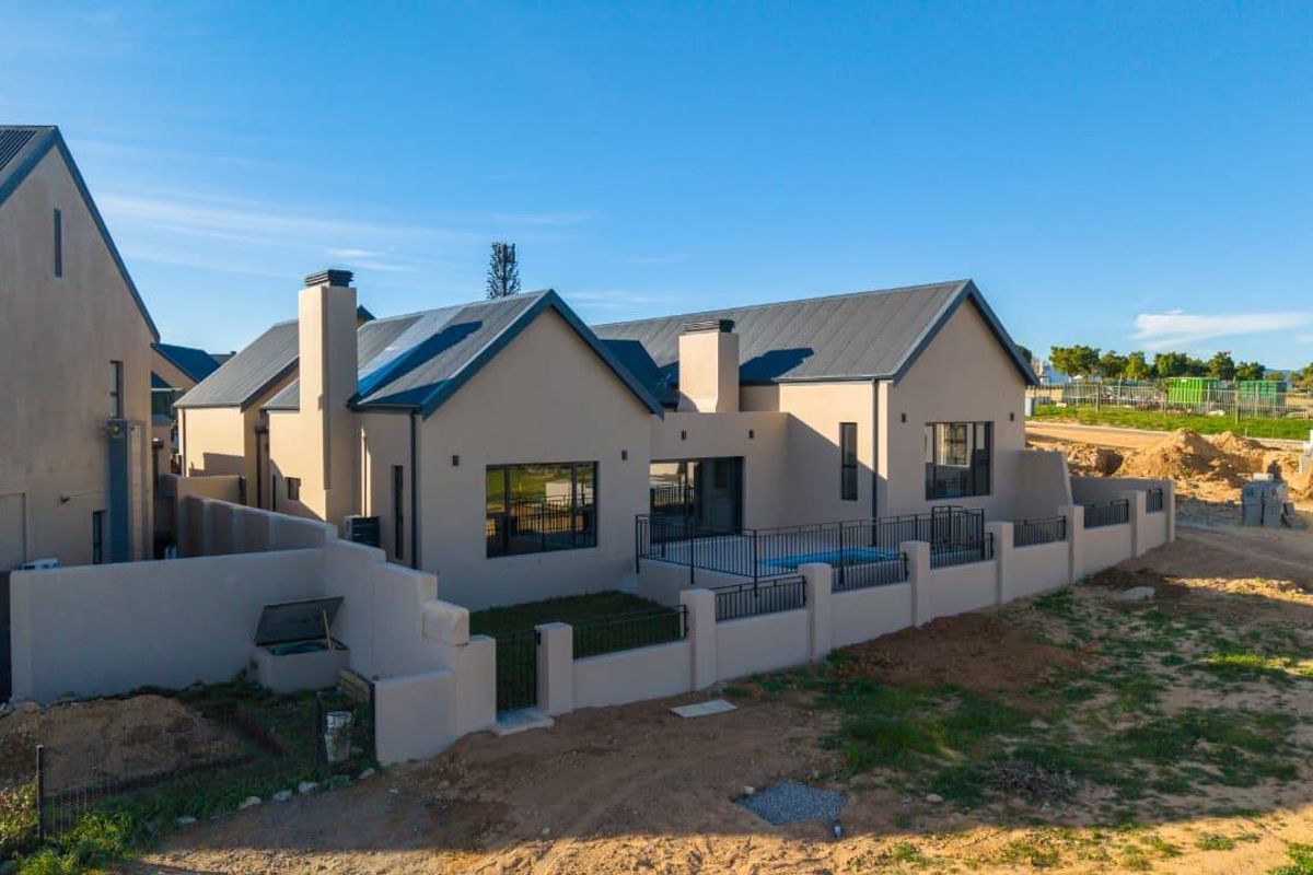 Aerial view of the rear elevation featuring a swimming pool, patio area, and perimeter walling with a modern metal roof design.