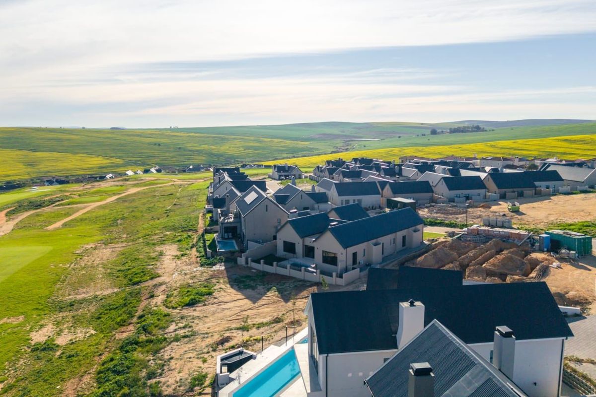 Aerial view of a modern residential estate featuring contemporary homes with pitched roofs, swimming pools, and surrounding landscaped golf course grounds.