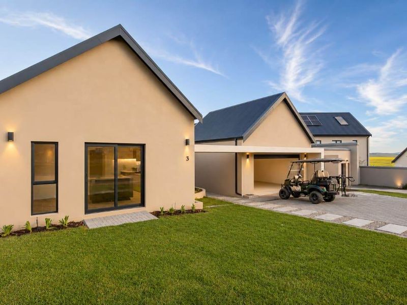 Modern single-story residence featuring a clean facade, paved driveway, covered carport, and well-maintained lawn in a contemporary estate setting.