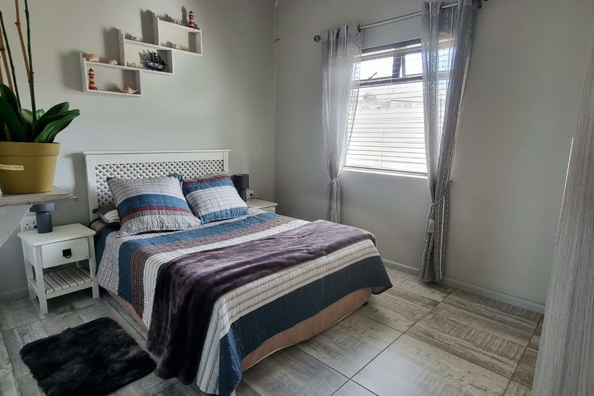 A well-maintained bedroom featuring tiled flooring and a window with fitted blinds, offering a clean and functional living space.