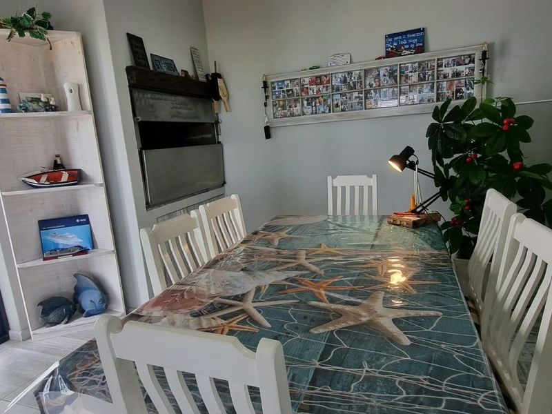 Dining area featuring tiled flooring, a built-in braai, and access to the outdoors via a glass sliding door.