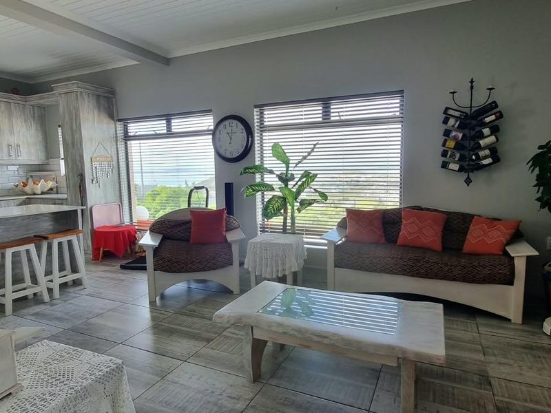 Spacious open-plan living area featuring a modern kitchen with a breakfast island, subway tile backsplash, and tiled flooring throughout.