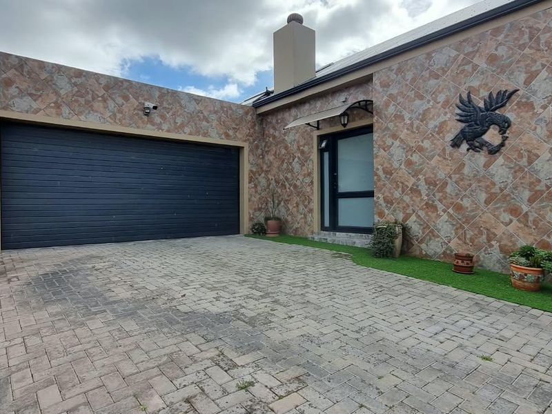 Front exterior view featuring a tiled facade, paved driveway, and an automated garage door with a covered entrance.