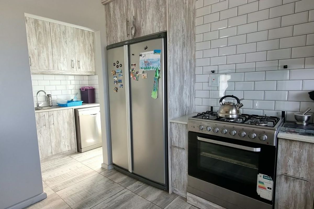 Modern kitchen featuring light wood-grain cabinetry, subway tile backsplash, stone countertops, and a stainless steel gas stove and oven combination.