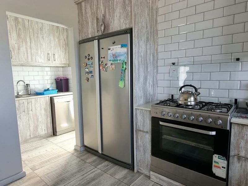 Modern kitchen featuring light wood-grain cabinetry, subway tile backsplash, stone countertops, and a stainless steel gas stove and oven combination.