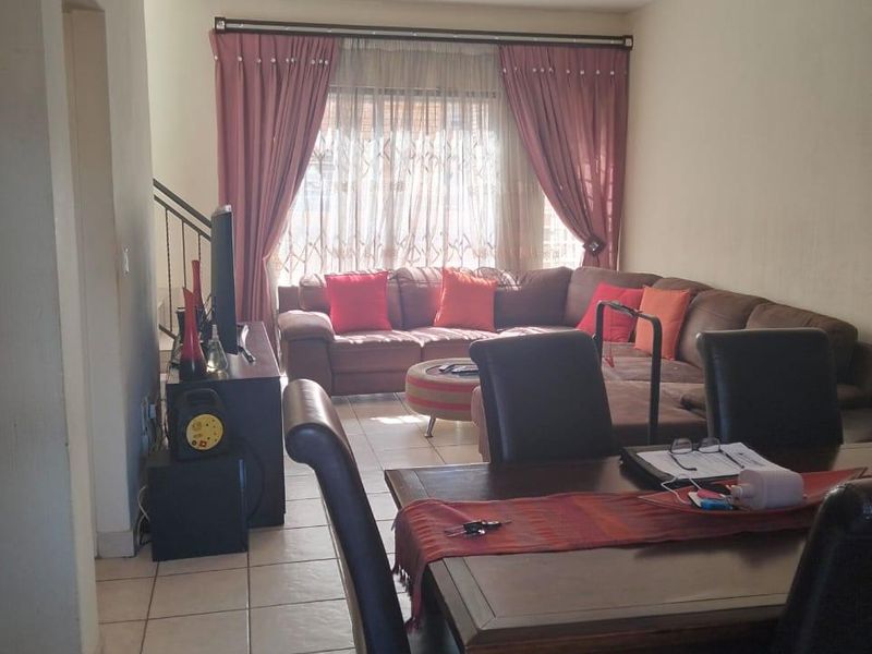 Open plan living and dining area featuring tiled flooring and a staircase, providing a functional layout for daily living.