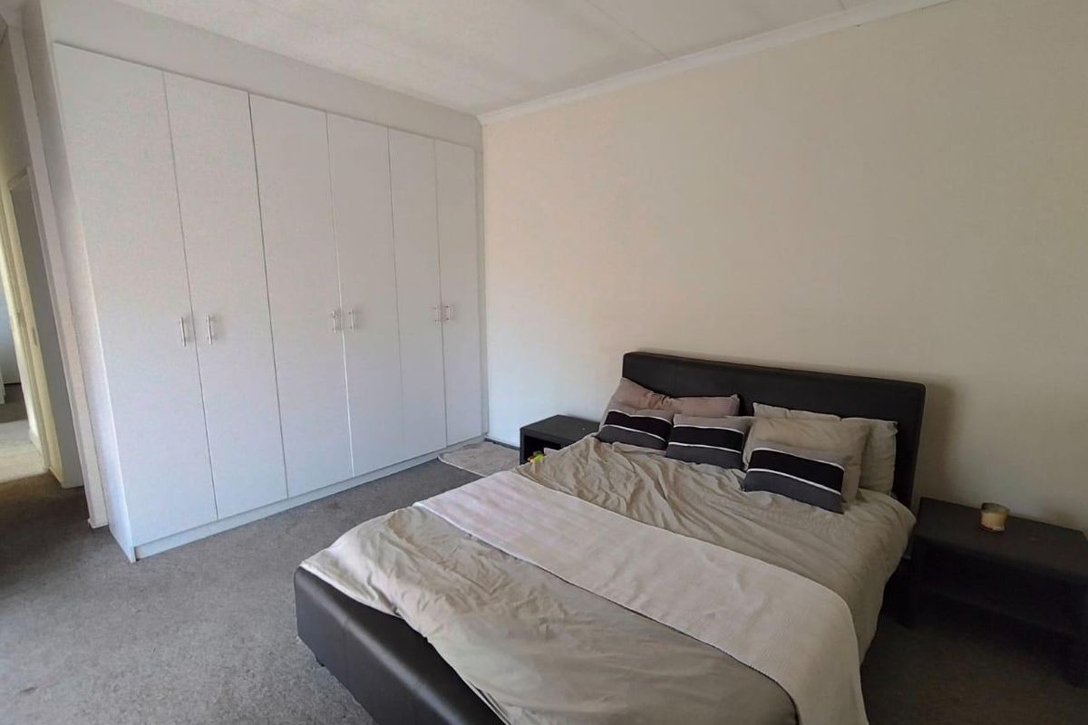 A functional bedroom featuring neutral walls, carpeted flooring, and ample built-in cupboard storage space.