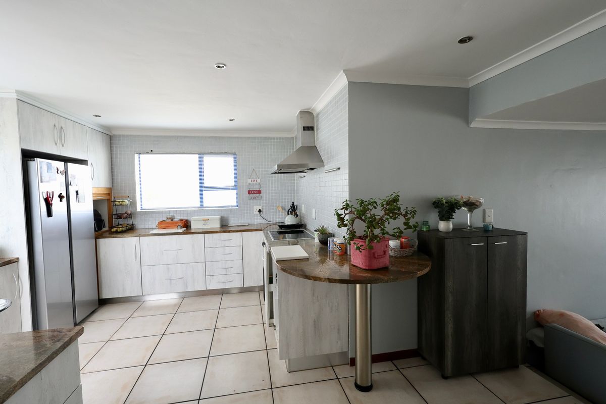 A functional kitchen featuring light-toned cabinetry, a tiled backsplash, a built-in hob with extractor fan, and a convenient breakfast bar area.