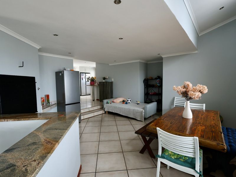 Open-plan living and dining area featuring tiled flooring, recessed lighting, and a built-in fireplace, with a seamless transition to the kitchen area.