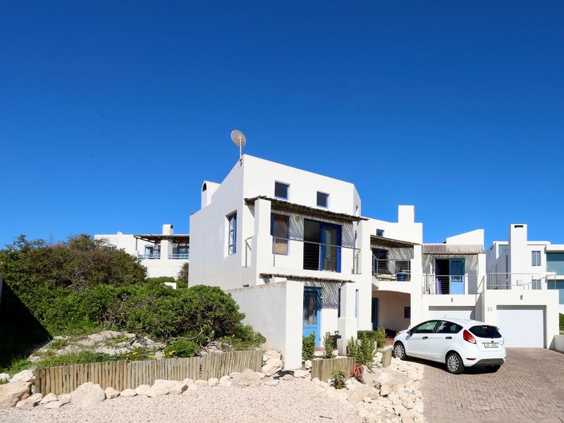 Front elevation of a multi-level residential property featuring white exterior walls, blue accents, paved driveway, and integrated garage.