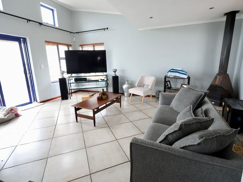 Spacious living room featuring tiled flooring, a modern freestanding fireplace, and large sliding glass doors providing ample natural light.