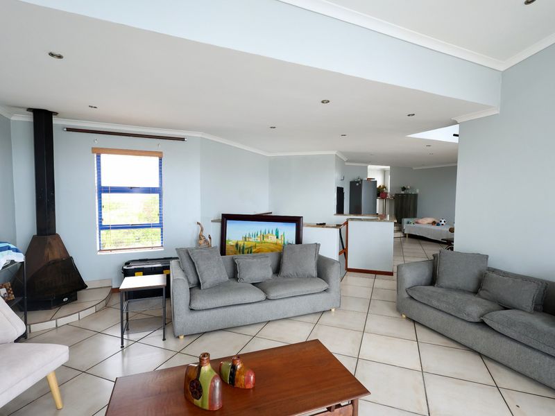 Spacious open-plan living area featuring tiled floors, a freestanding fireplace, and a connected kitchen space with a breakfast counter.