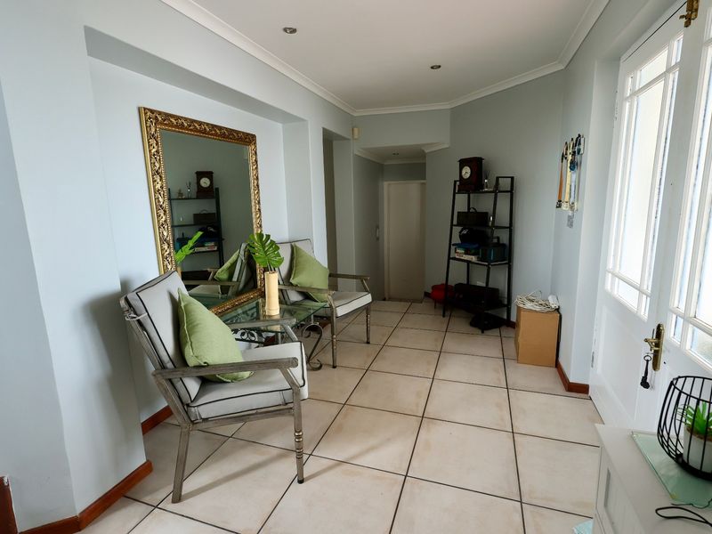 A bright entrance hall featuring tiled flooring, recessed downlighting, and a glass-panelled door leading to the exterior.