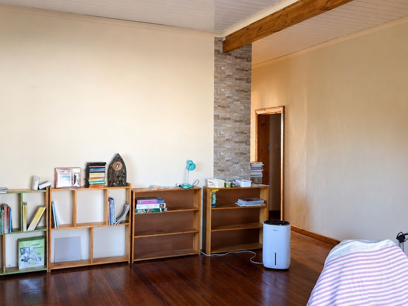 A living area featuring polished timber flooring, an exposed wooden ceiling beam, and a decorative stone veneer pillar.