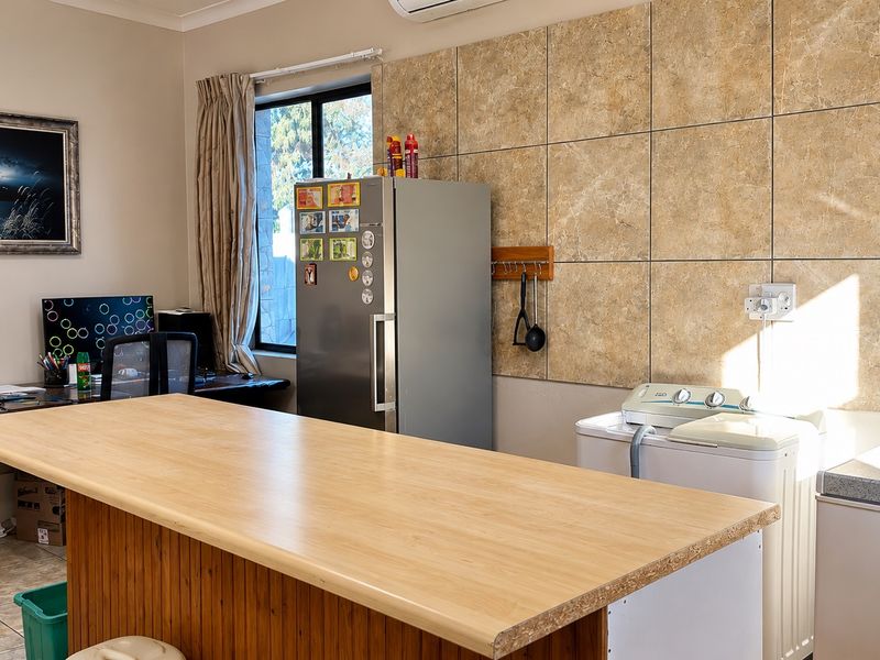 A functional laundry area featuring tiled wall finishes, an air conditioning unit, and a central workspace counter.
