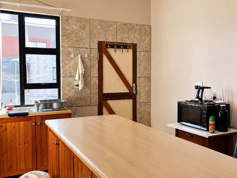 A functional scullery area featuring wooden cabinetry, a stainless steel sink, and tiled splashback, providing additional prep and utility space.