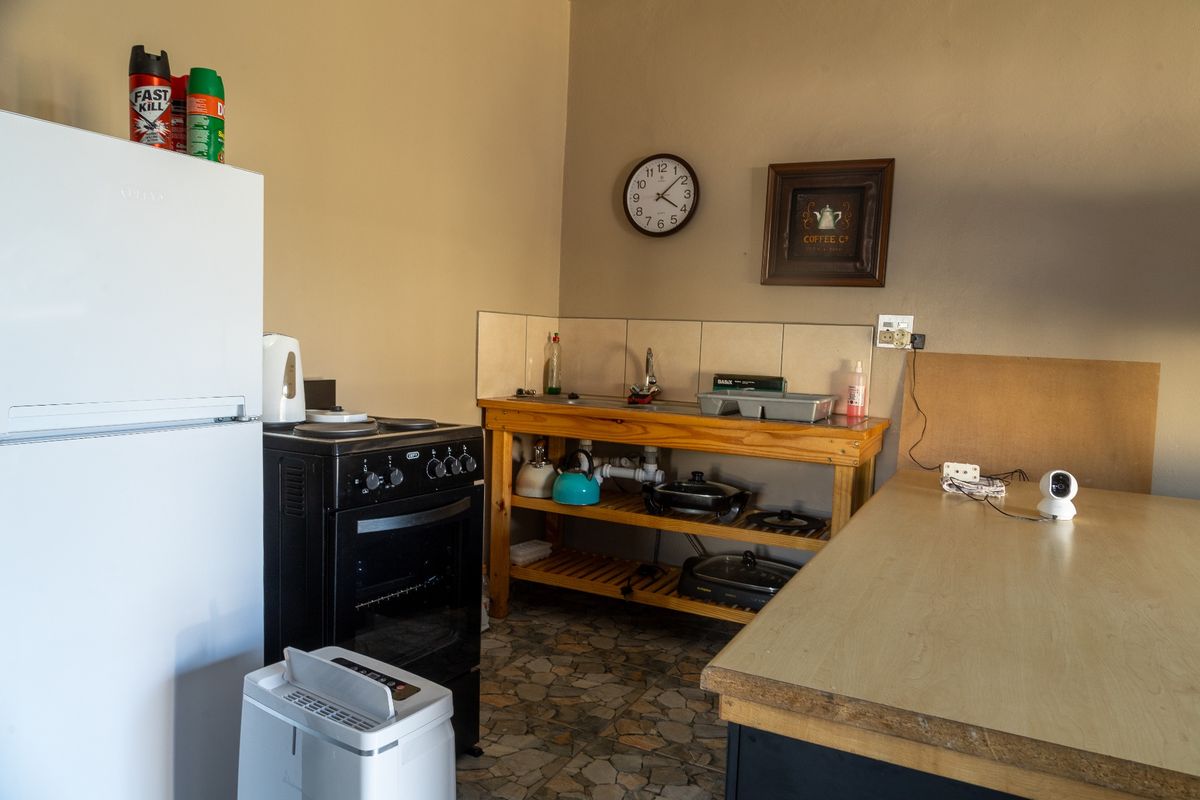 A functional kitchen area featuring a freestanding stove, a wooden prep station with an integrated sink, and tiled splashbacks.