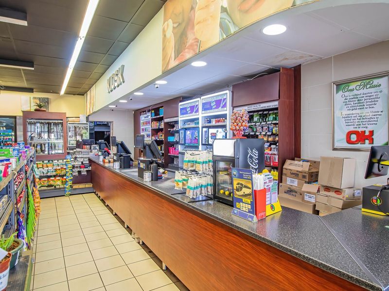 A commercial retail service counter area featuring tiled flooring, built-in shelving, and integrated service points within a retail store environment.