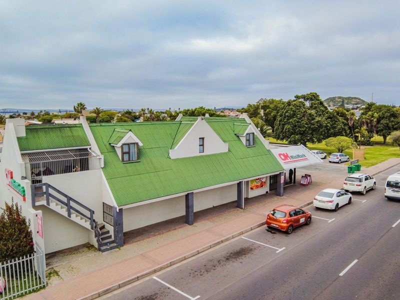 Aerial view of a commercial property featuring a green corrugated roof, external staircase, and dedicated street-level parking.