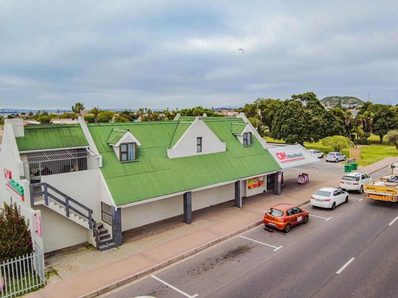 Aerial view of a commercial property featuring a green metal roof, external staircase, and dedicated street-side parking.