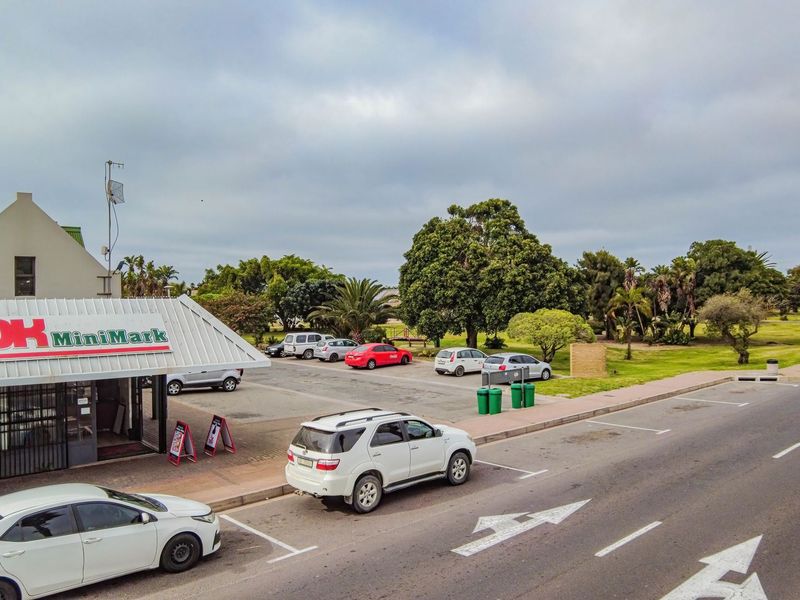 Aerial view of a commercial retail property featuring a paved parking area, corrugated metal roofing, and prominent storefront signage.