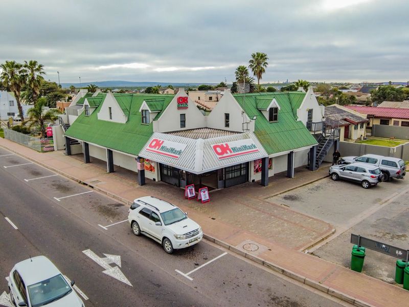 Aerial view of a commercial corner property featuring a green metal roof, paved parking area, and external access staircase.