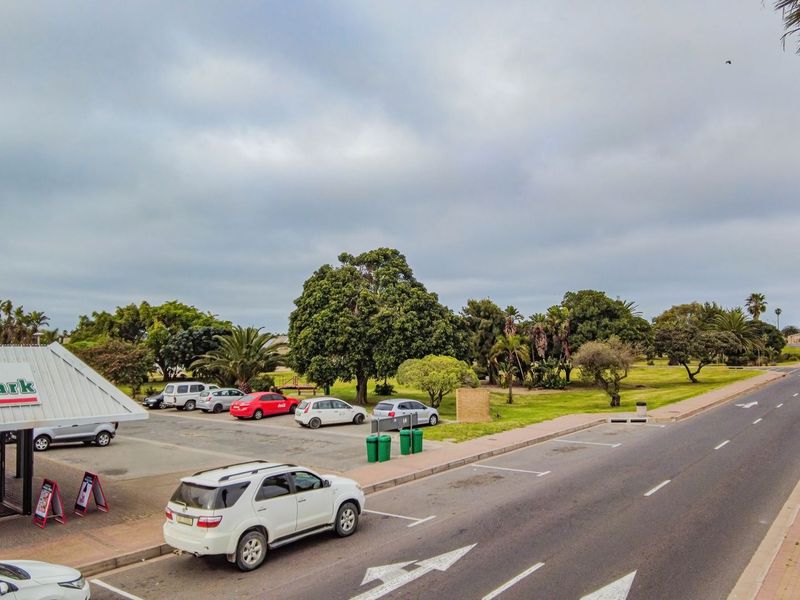 Street-level view of a commercial property featuring a MiniMark storefront, adjacent parking area, and surrounding landscaped grounds along a public road.