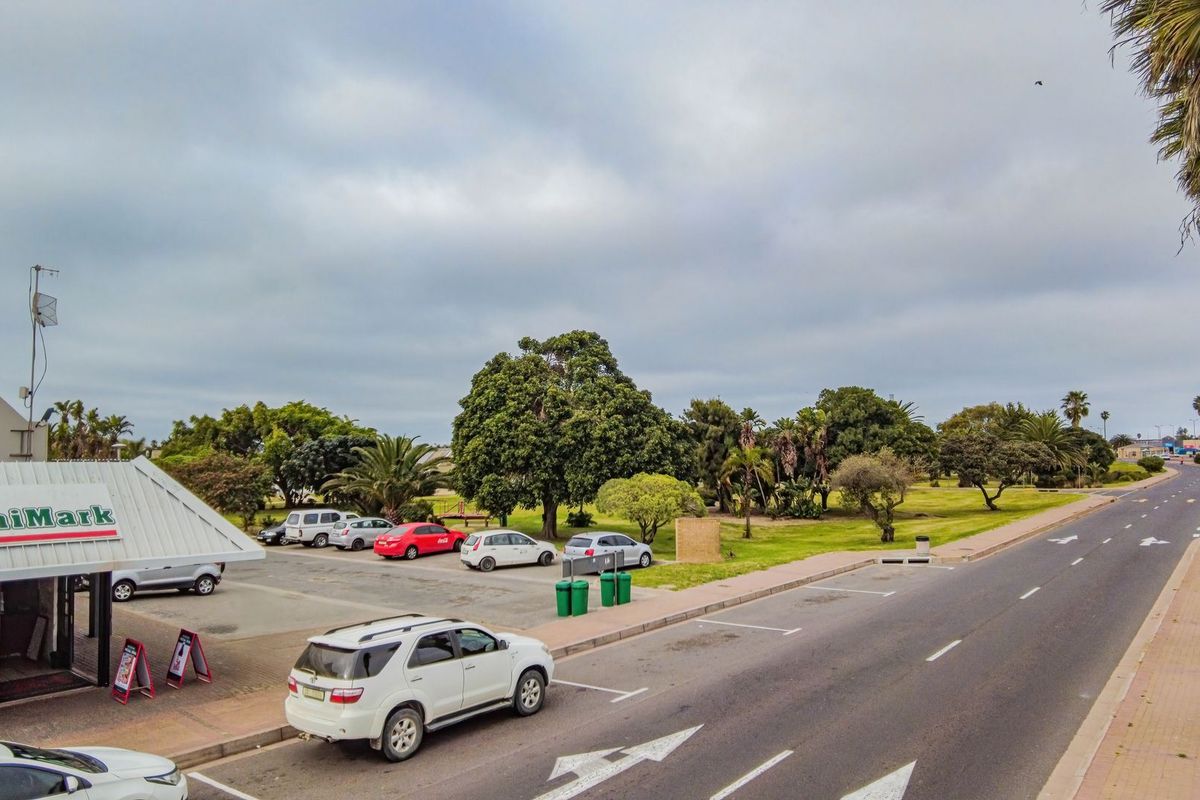 Street-level view of a commercial property featuring a MiniMark storefront, adjacent parking area, and surrounding landscaped grounds along a public road.