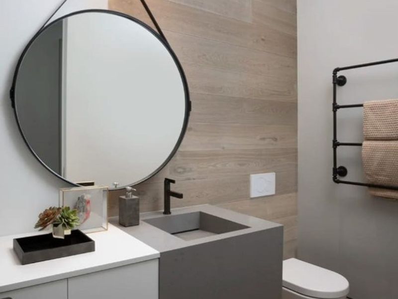 Modern bathroom featuring a wall-mounted vanity with integrated concrete basin, wall-hung toilet, heated towel rail, and stylish timber-look wall accents.