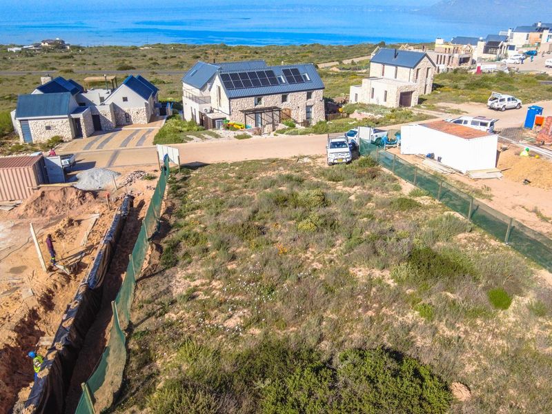Aerial view of a vacant residential plot in a coastal estate, showing surrounding development and active site preparation.
