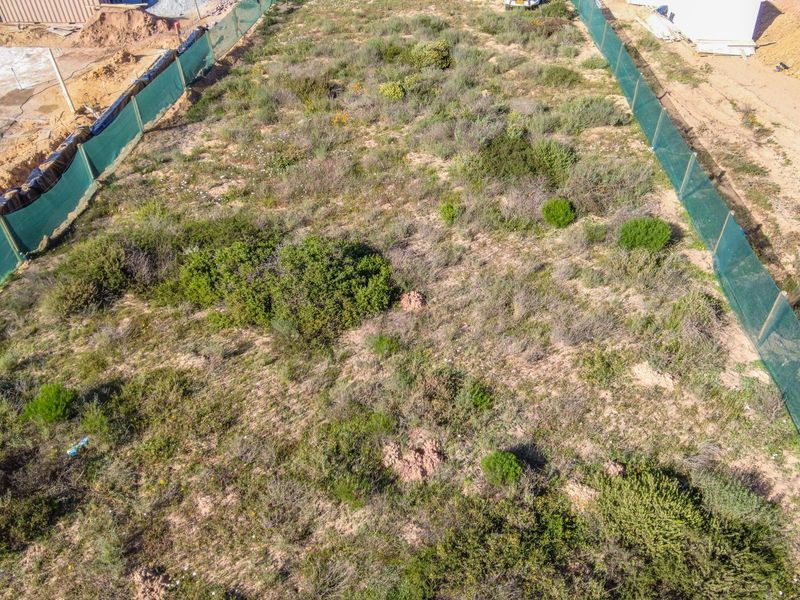 Aerial view of a vacant residential plot featuring perimeter fencing and natural vegetation, ready for development.