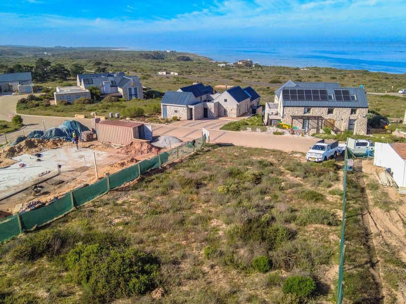 Aerial view of a residential vacant land plot under construction, featuring a concrete foundation and proximity to the coastline.