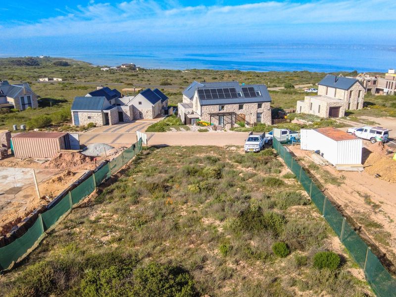 Aerial view of a vacant residential plot in a coastal estate, showing surrounding development and natural landscape.