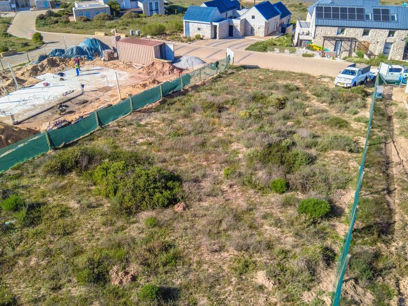 Aerial view of a vacant residential plot featuring a concrete foundation slab and perimeter fencing in a developing estate.