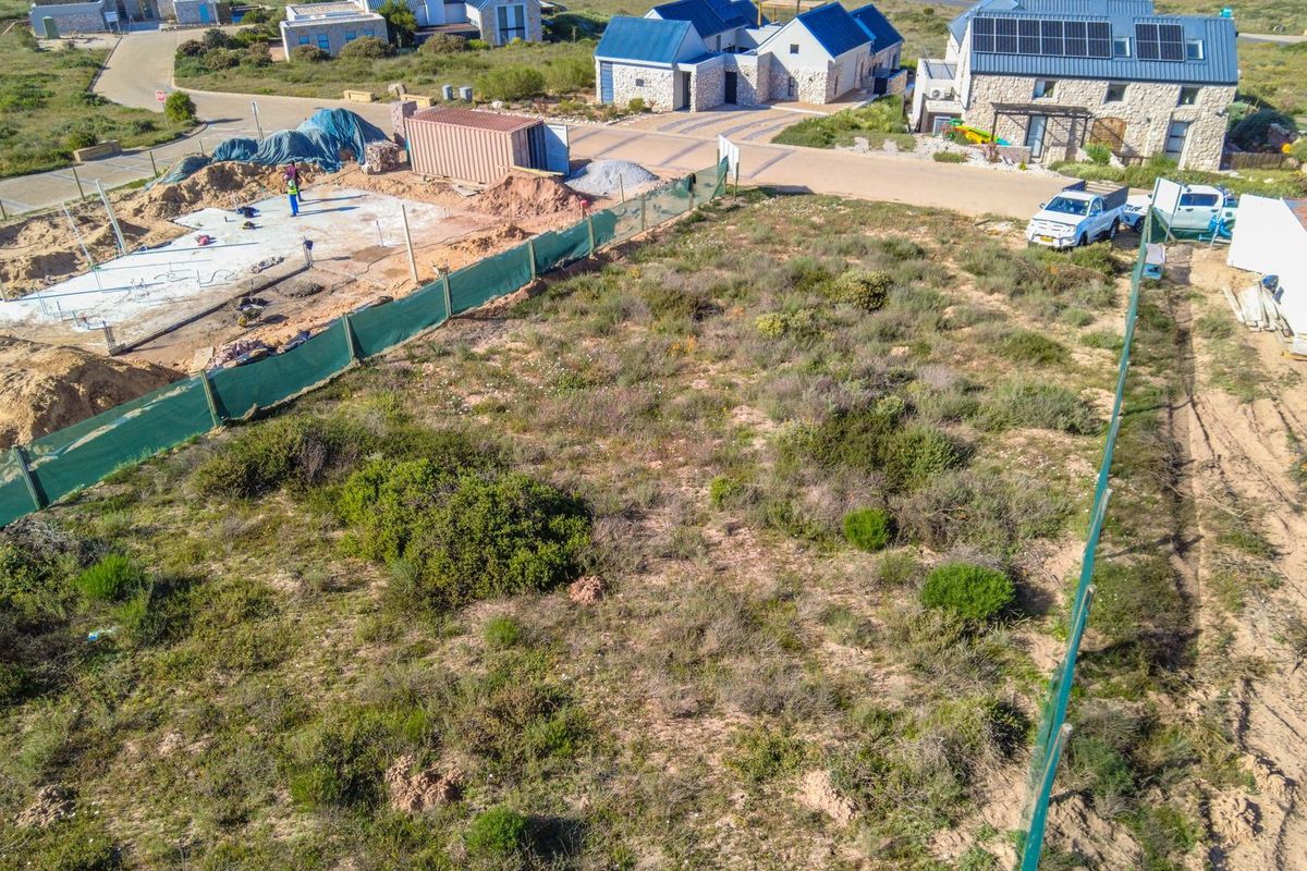 Aerial view of a vacant residential plot featuring a concrete foundation slab and perimeter fencing in a developing estate.