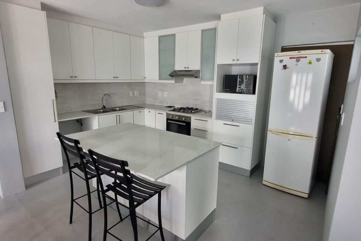 Modern kitchen featuring white cabinetry, stone countertops, a central island, and integrated appliances including a gas hob and oven.