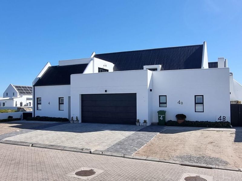 Modern white exterior facade featuring a double garage, dark roof, and paved driveway area.