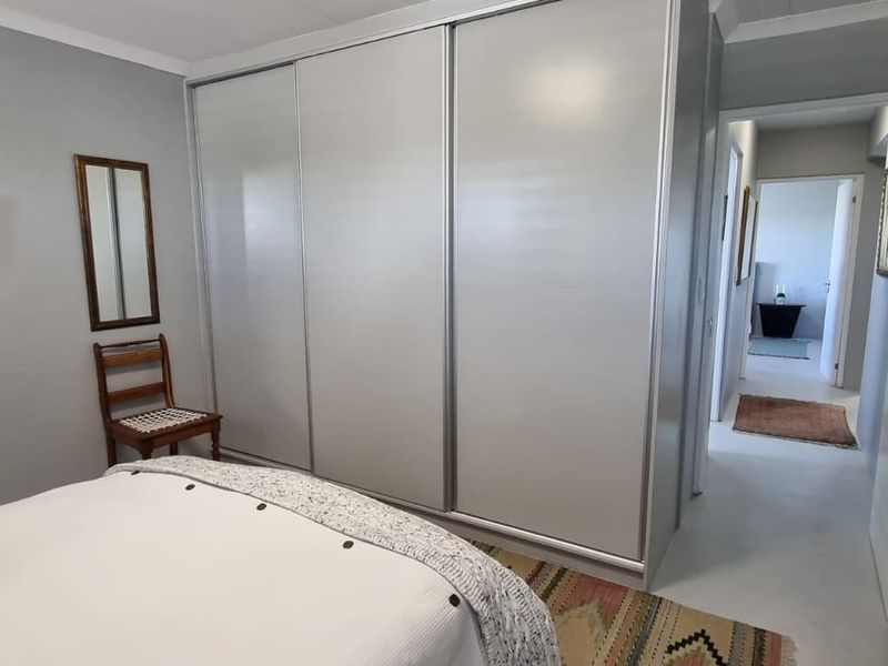 A bedroom featuring a large built-in sliding door wardrobe and neutral wall finishes, with a view leading into the hallway.