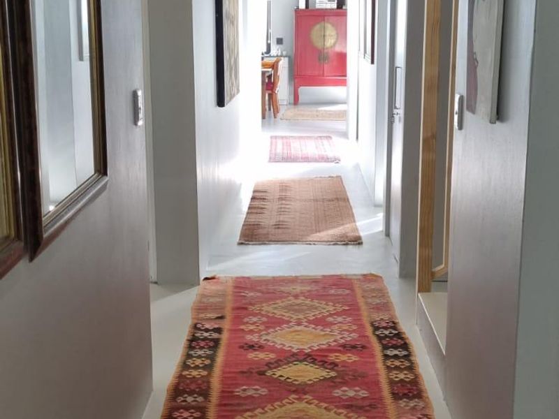 A long, well-lit hallway featuring neutral wall tones and tiled flooring, providing a clean transition between the home's living spaces.