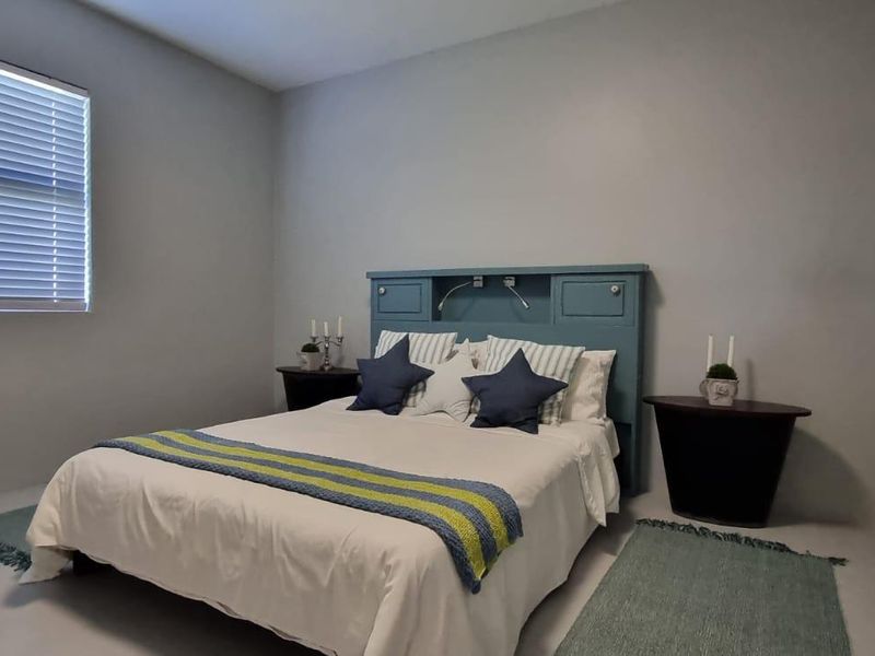 A simple bedroom featuring a built-in headboard and venetian blinds, providing a functional and neutral space.