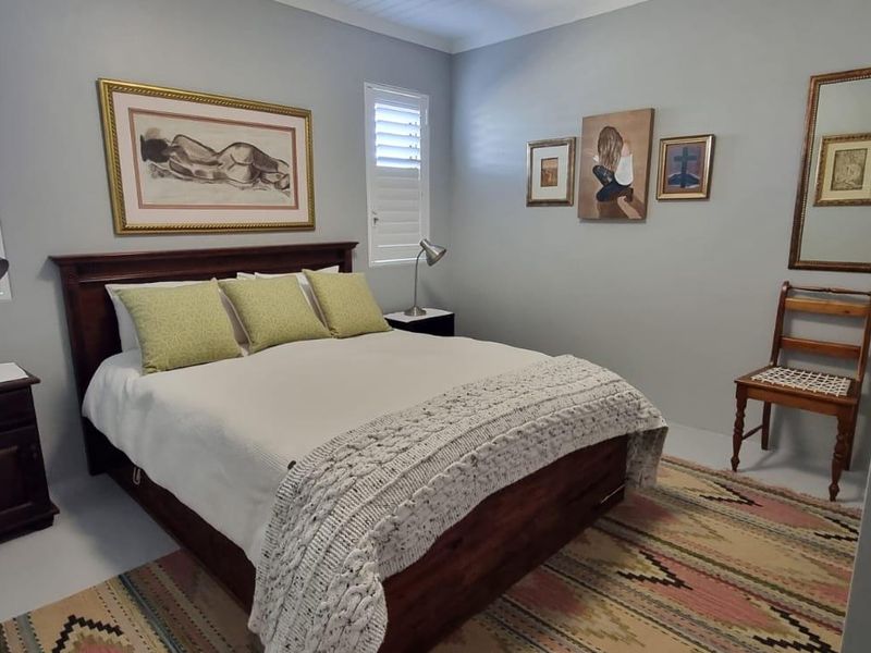 A well-maintained bedroom featuring neutral wall tones and white plantation shutters, providing a clean and comfortable living space.