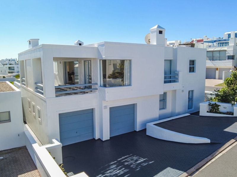 A modern two-story residential property featuring a double garage, paved driveway, and an upper-level balcony with clean white architectural lines.