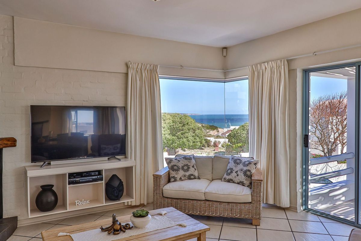 Bright living room featuring a corner window with ocean views, tiled flooring, and direct access to an outdoor patio area.