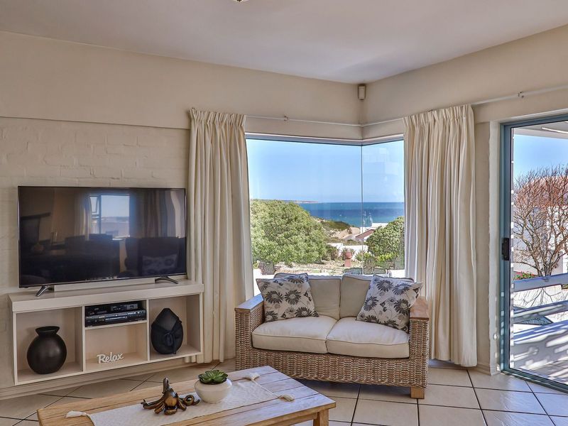 Bright living room featuring a corner window with ocean views, tiled flooring, and direct access to an outdoor patio area.